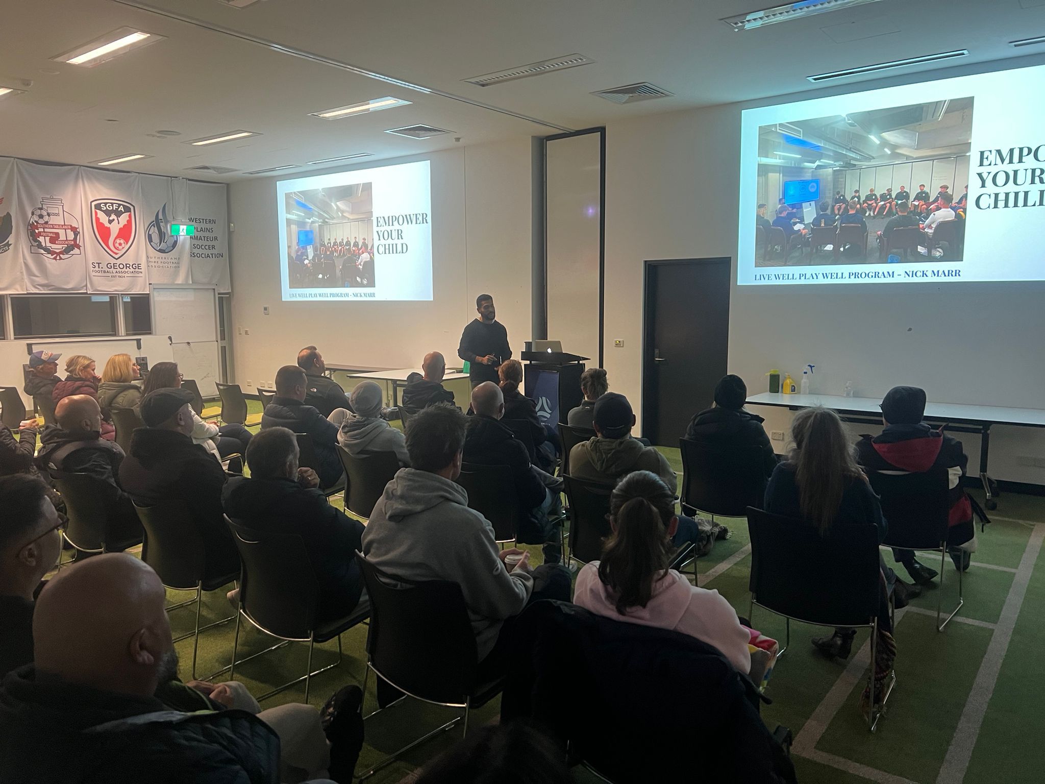 Parents at a Football NSW session run by Nick Marr, federation banners on the wall